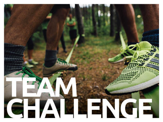 Gruppe mit grünen Turnschuhen auf Slackline bei der Team Challenge